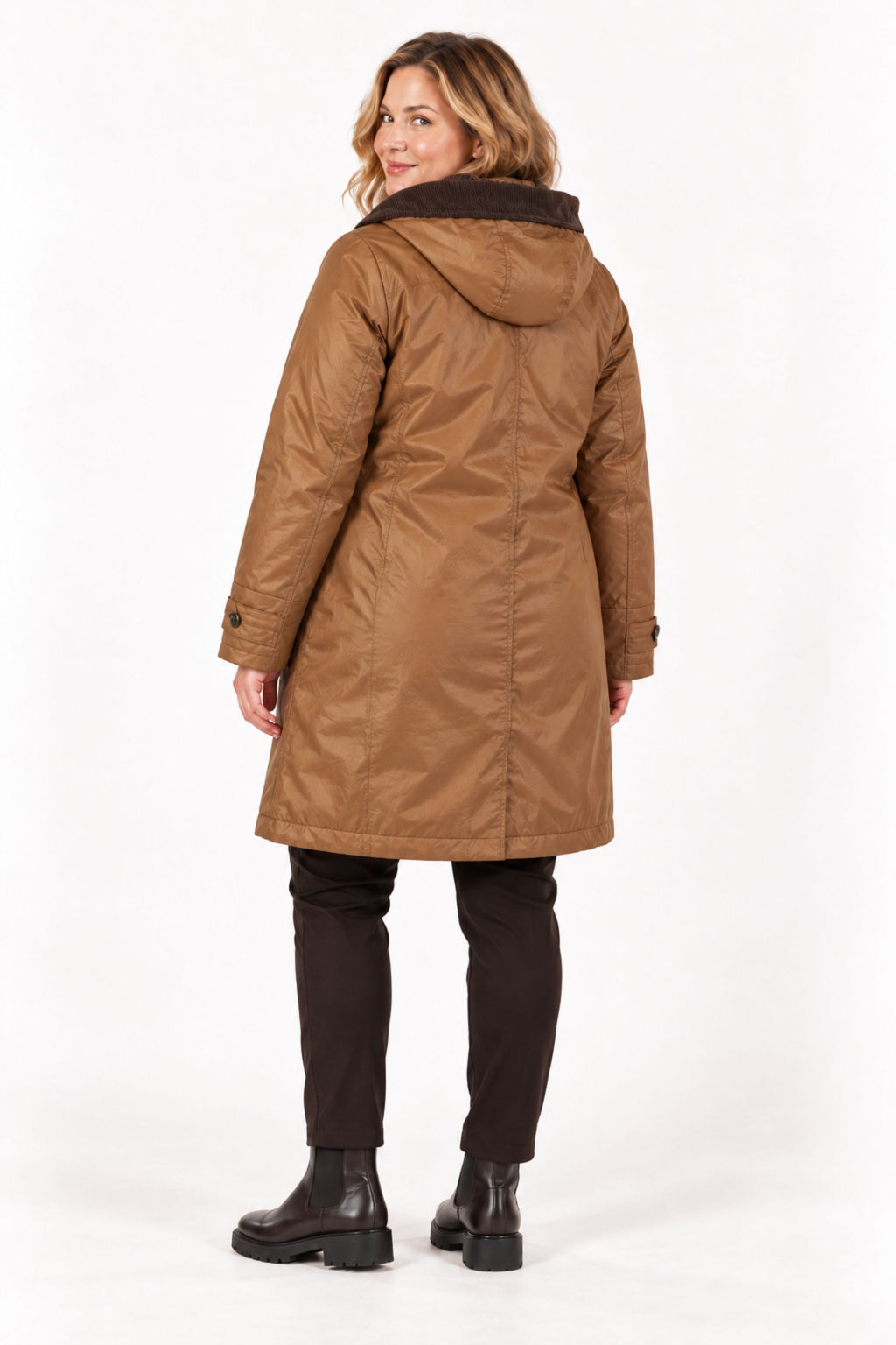 A woman shown from the back wearing a mid-length brown hooded coat with a dark brown faux-fur collar, paired with dark pants and black boots, against a plain white studio background.